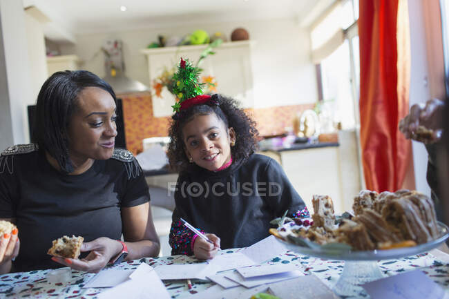 Portrait mother and daughter writing Christmas cards at table — Stock Photo