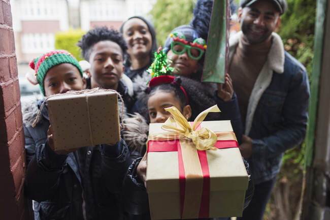 Portrait happy family delivering Christmas gifts at front stoop — Stock Photo