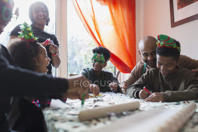 Happy family decorating Christmas cookies at table — Stock Photo