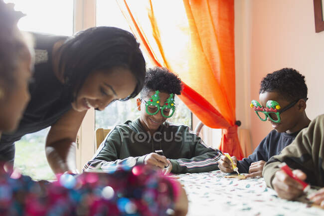 Fröhliche Festtagsfamilie schmückt Weihnachtsplätzchen am Tisch — Stockfoto