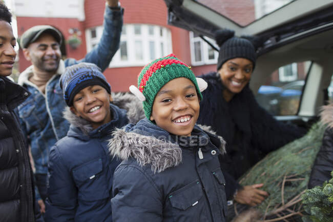 Portrait happy family loading Christmas tree in car — Stock Photo