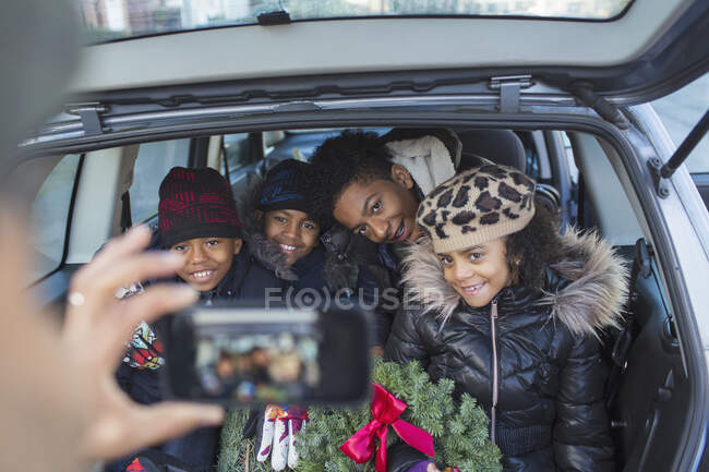 Glückliche Familie mit Weihnachtskranz posiert für Foto im Auto — Stockfoto