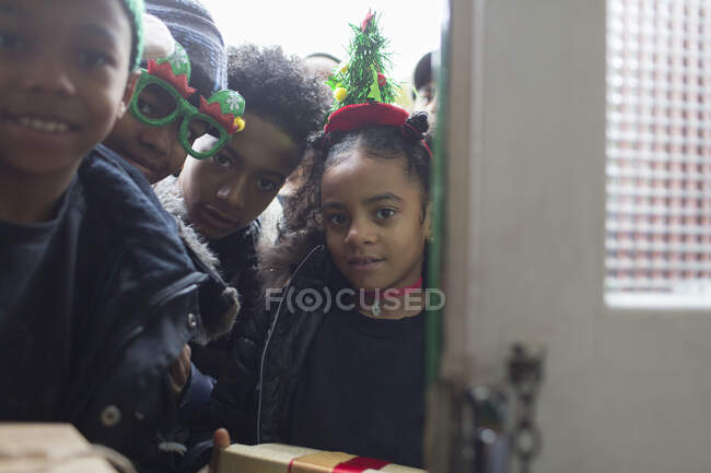Portrait brothers and sister with Christmas gifts at front door — Stock Photo