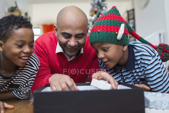 Father and sons opening Christmas gift — Stock Photo