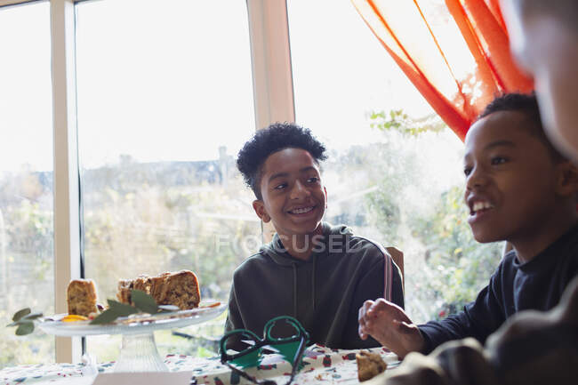 Felices hermanos comiendo pastel en la mesa - foto de stock