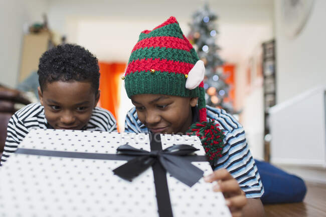Curious brothers peeking at Christmas gift — Stock Photo