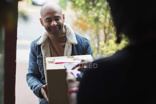 Entrega homem entregando pacote para mulher na porta da frente — Fotografia de Stock
