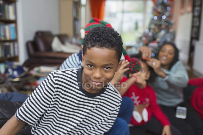 Retrato juguetón niño celebrando la Navidad con la familia en la sala de estar - foto de stock