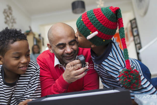 Glücklicher Sohn küsst Vater beim Öffnen von Weihnachtsgeschenk — Stockfoto