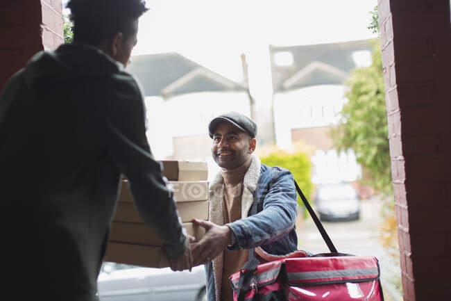 Friendly food delivery man with boxes at front door — Stock Photo