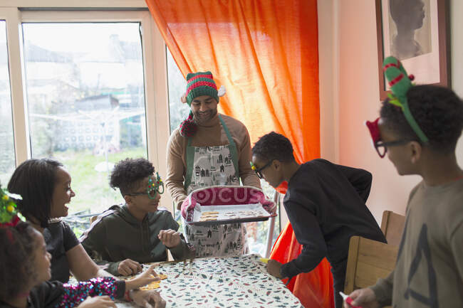 Святкова родина прикрашає різдвяне печиво за столом — стокове фото