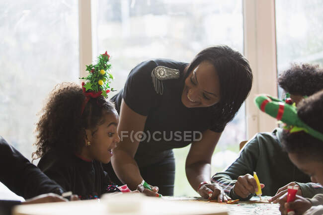 Feliz madre e hija decorando galletas de Navidad en la mesa - foto de stock