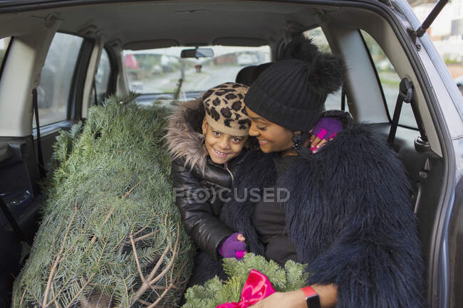 Retrato mãe feliz e filha no carro com árvore de Natal — Fotografia de Stock