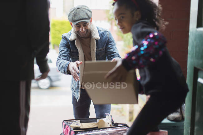 Girl receiving pizza delivery from delivery man at front door — Stock Photo