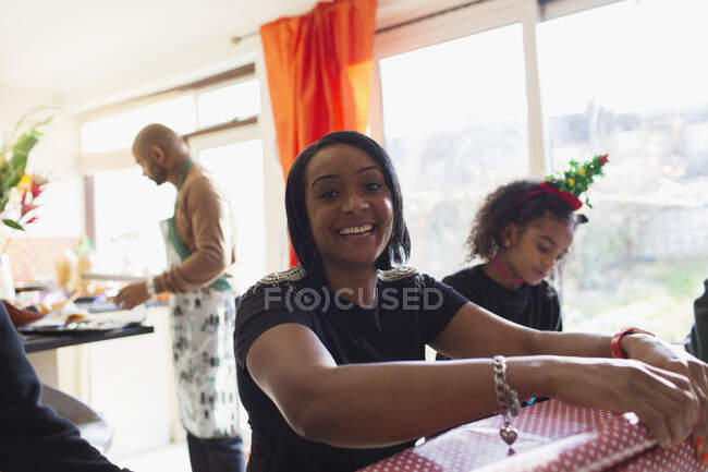 Portrait happy woman wrapping Christmas gifts with family — Stock Photo