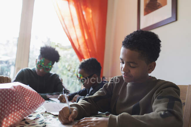 Junge schreibt Weihnachtskarten am Tisch — Stockfoto