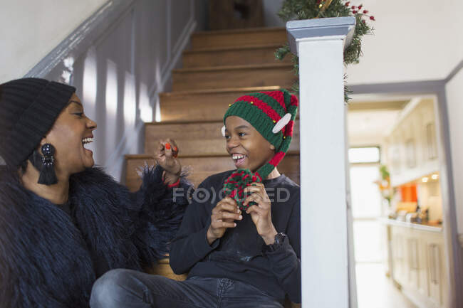 Счастливая мать и сын в рождественской шляпе на лестнице — стоковое фото