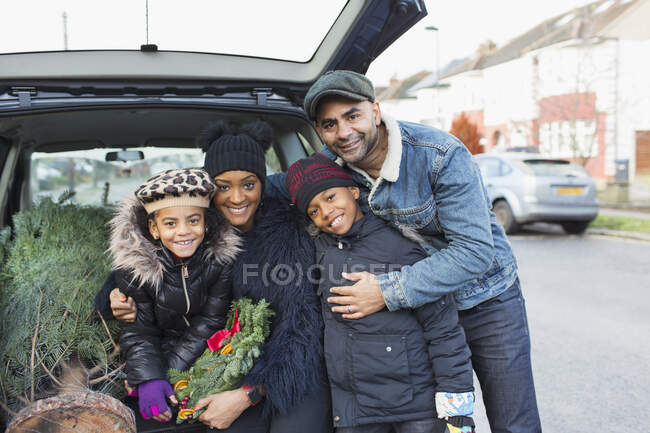 Portrait happy family loading Christmas tree in back of car — Stock Photo
