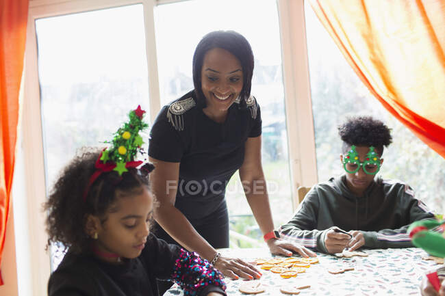 Happy mother and children decorating Christmas cookies at table — Stock Photo