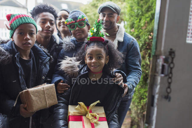 Retrato feliz familia entrega regalos de Navidad en la puerta principal - foto de stock