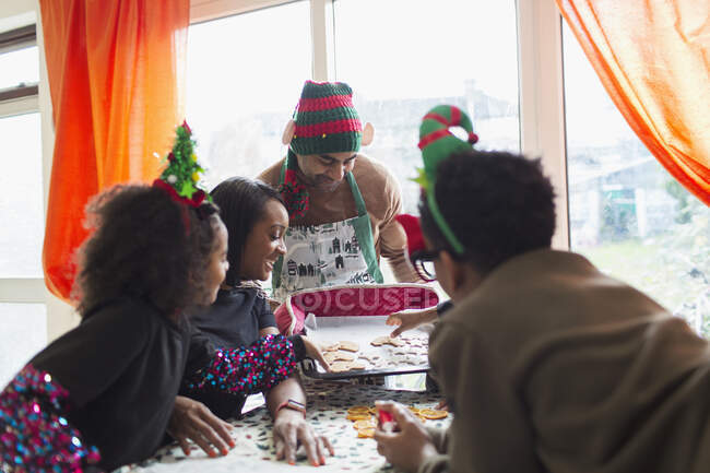 Feliz familia decorando galletas de Navidad en la mesa - foto de stock