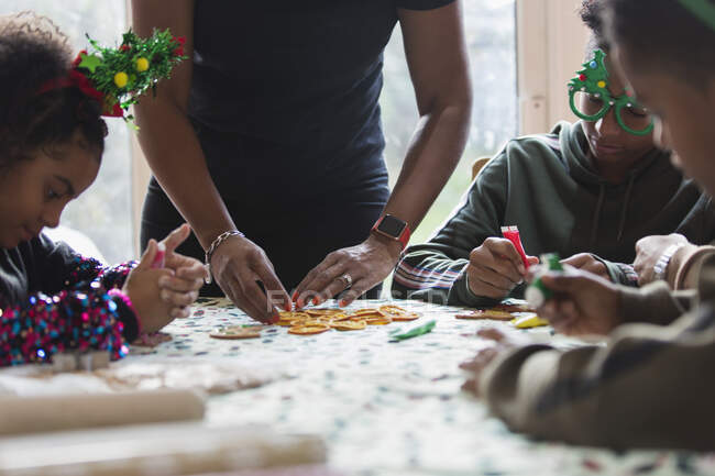 Familie schmückt Weihnachtsplätzchen am Tisch — Stockfoto