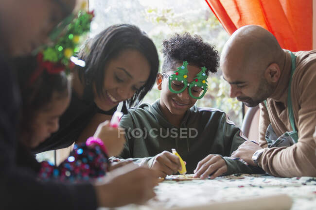 Festliche Familie schmückt Weihnachtsplätzchen am Tisch — Stockfoto