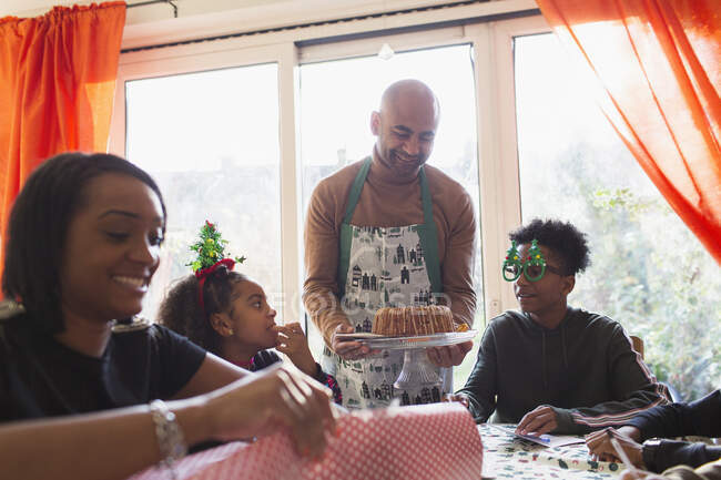 Father serving Christmas cake to family at table — Stock Photo