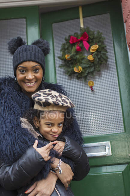 Retrato mãe feliz e filha na porta da frente com grinalda de Natal — Fotografia de Stock