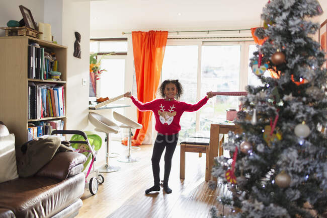 Retrato chica feliz en suéter de Navidad sosteniendo papel de regalo - foto de stock