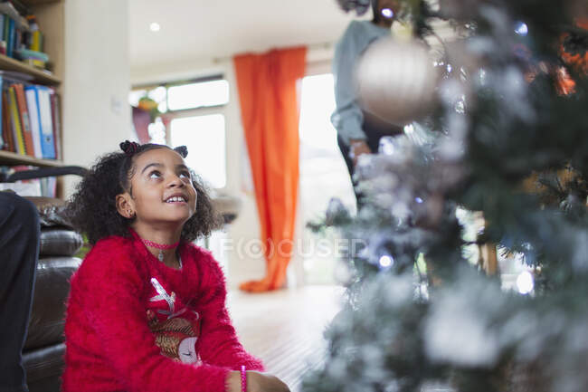 Curious girl looking up at Christmas tree — Stock Photo