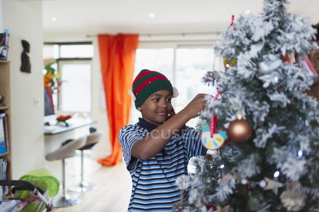 Junge schmückt Weihnachtsbaum im Wohnzimmer — Stockfoto