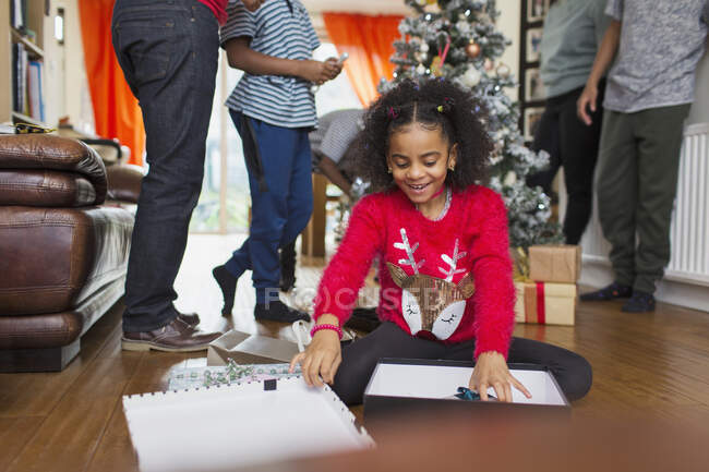 Aufgeregtes Mädchen öffnet Weihnachtsgeschenk auf Wohnzimmerboden — Stockfoto