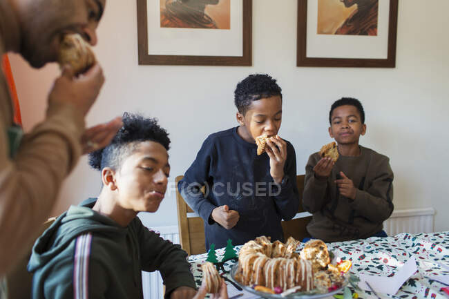 Father and sons eating Christmas cake at table — Stock Photo