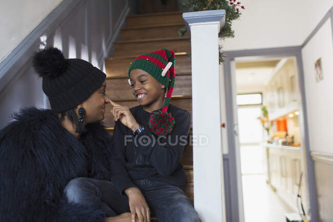 Madre e hijo juguetones en sombrero de Navidad en las escaleras - foto de stock