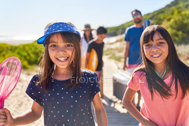 Portrait happy sisters on sunny beach with family — Stock Photo