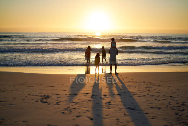 Familie watet im Sommer in der Brandung des Meeres bei Sonnenuntergang — Stockfoto