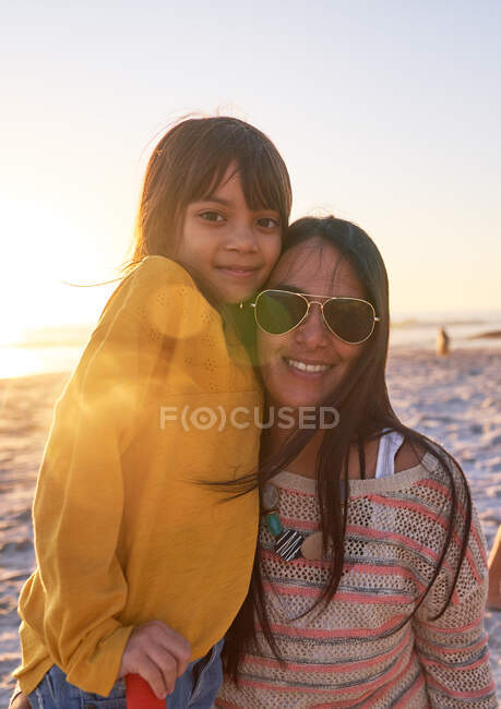Retrato feliz madre e hija en la playa soleada al atardecer - foto de stock
