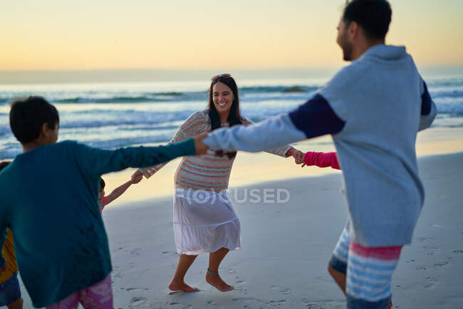 Familia feliz cogida de la mano en círculo en la playa - foto de stock