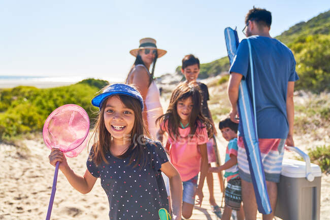 Portrait happy girl with butterfly net on sunny beach with family — Stock Photo