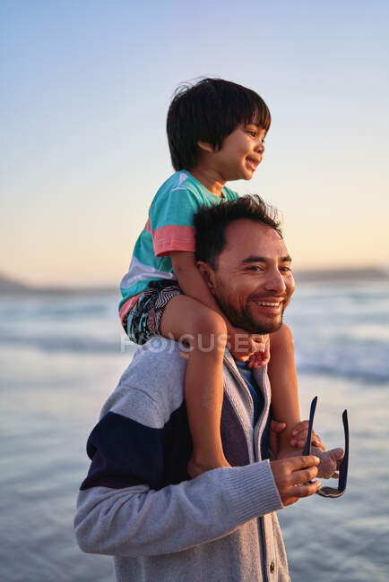 Happy father carrying son on shoulders on ocean beach — Stock Photo