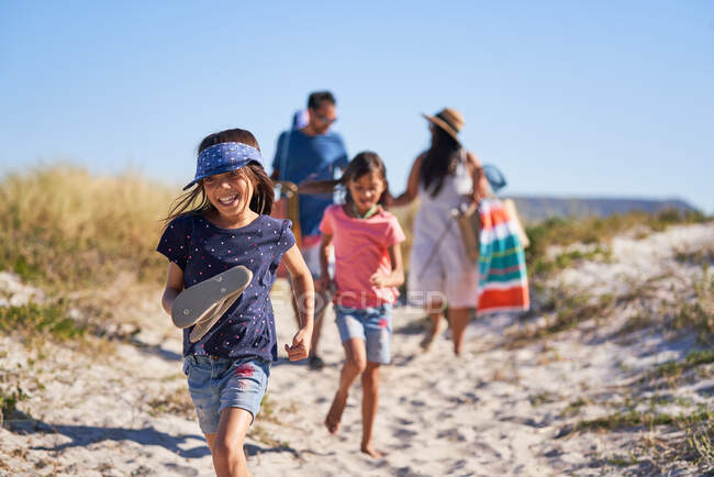 Glückliches Mädchen läuft mit Familie am sonnigen Strand — Stockfoto