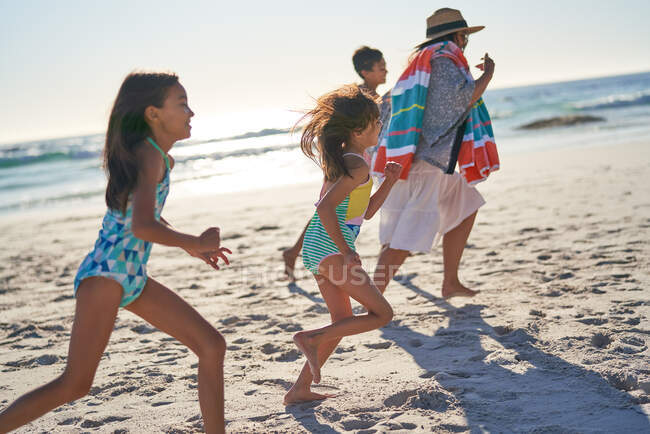 Família brincalhão correndo na praia ensolarada do oceano — Fotografia de Stock
