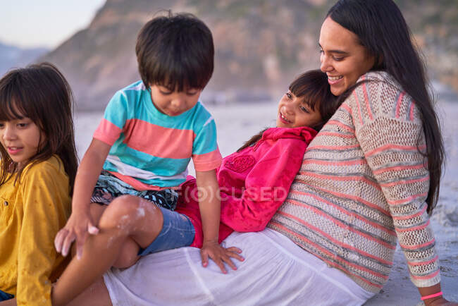 Счастливая мама и дети отдыхают на пляже — стоковое фото