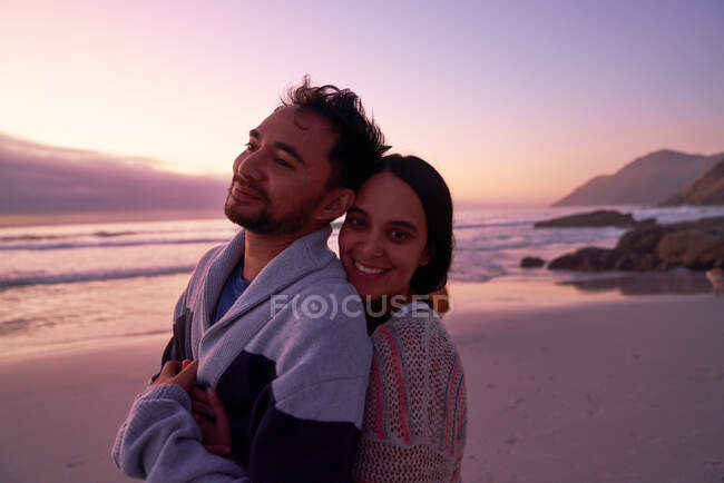 Portrait happy affectionate couple hugging on beach at sunset — Stock Photo