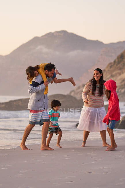 Счастливая семья играет на океанском пляже — стоковое фото