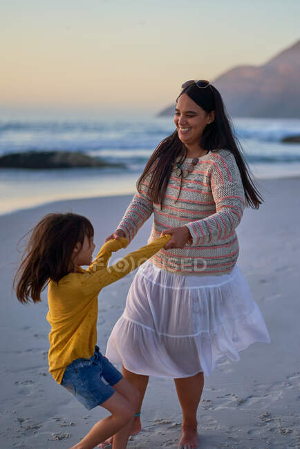 Madre juguetona e hija bailando en la playa - foto de stock