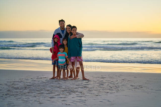 Retrato familia feliz en la playa del océano al atardecer - foto de stock