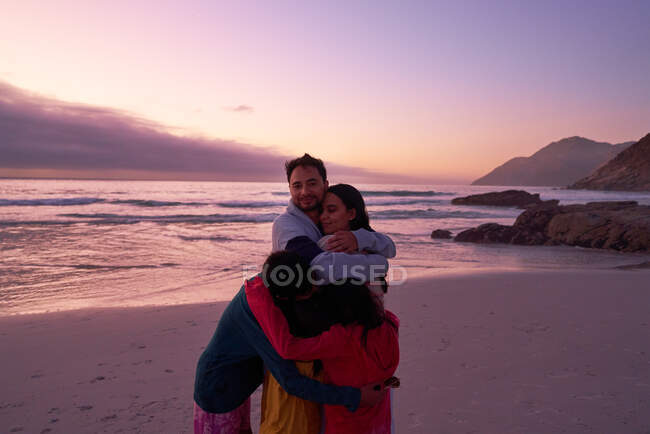 Portrait happy family hugging on sunset ocean beach, Cape Town — Stock Photo