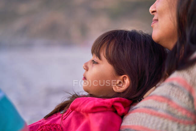 Закрыть дочь, отдыхающую у матери на пляже — стоковое фото